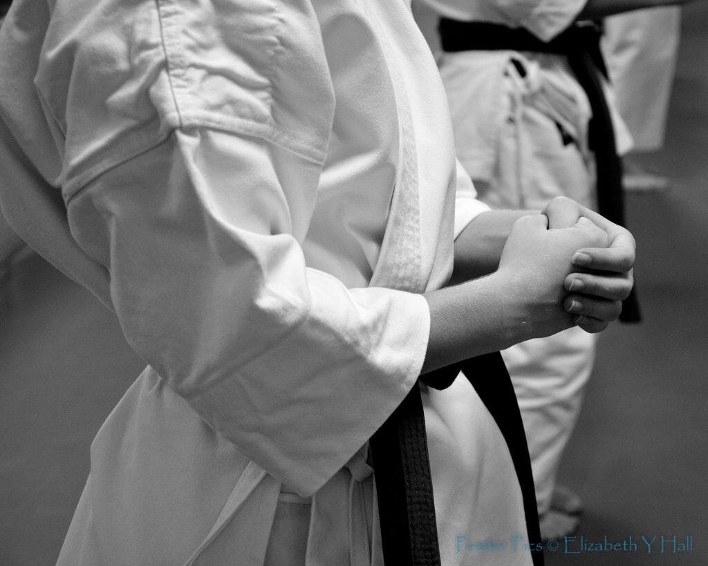 Close up of woman wearing martial arts robe with black belt in karate
