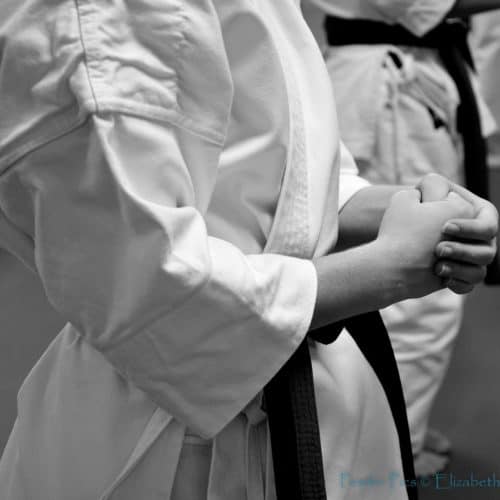 Close up of woman wearing martial arts robe with black belt in karate