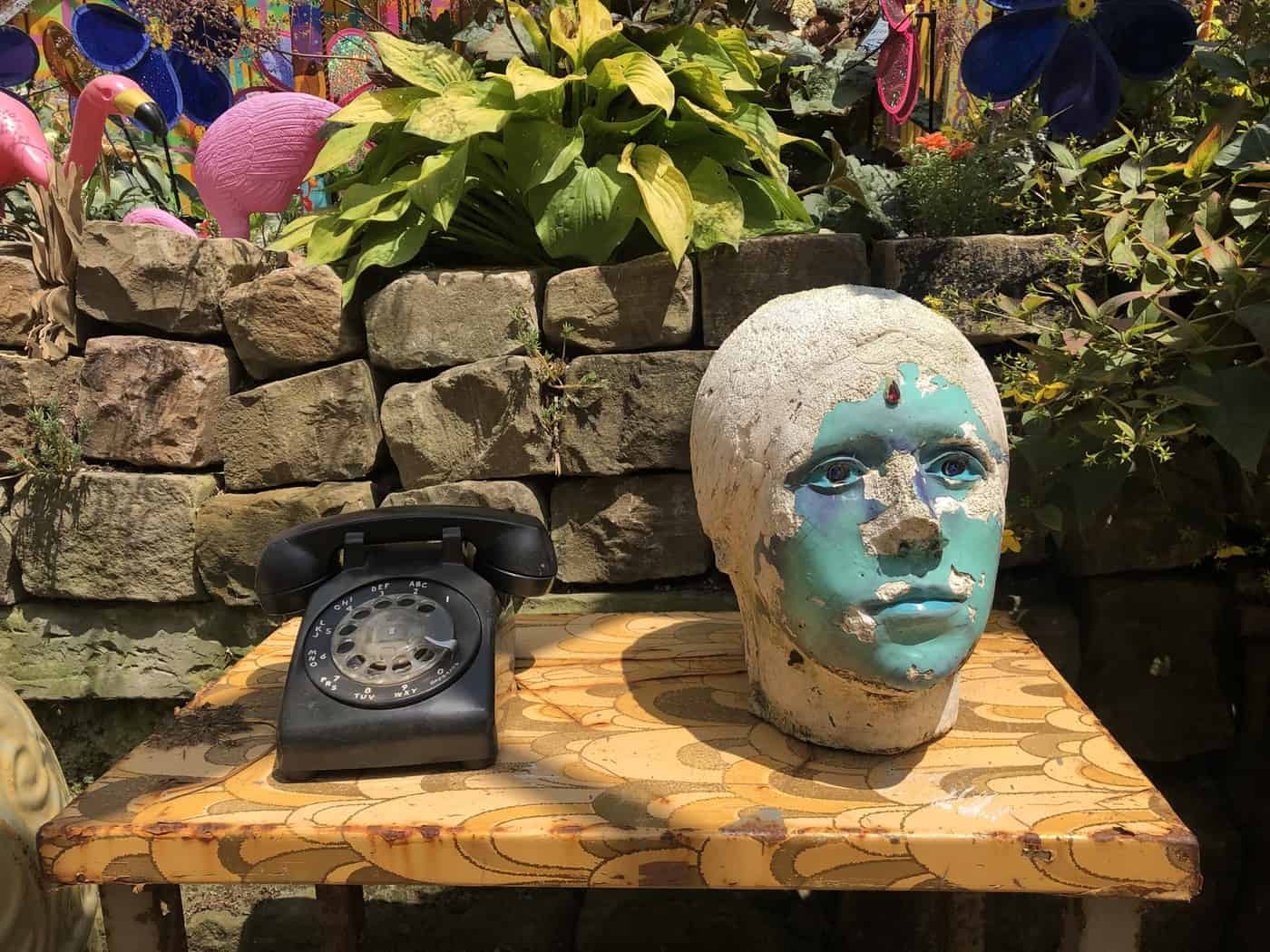 Wooden table with old rotary telephone and statue head with paint peeling off